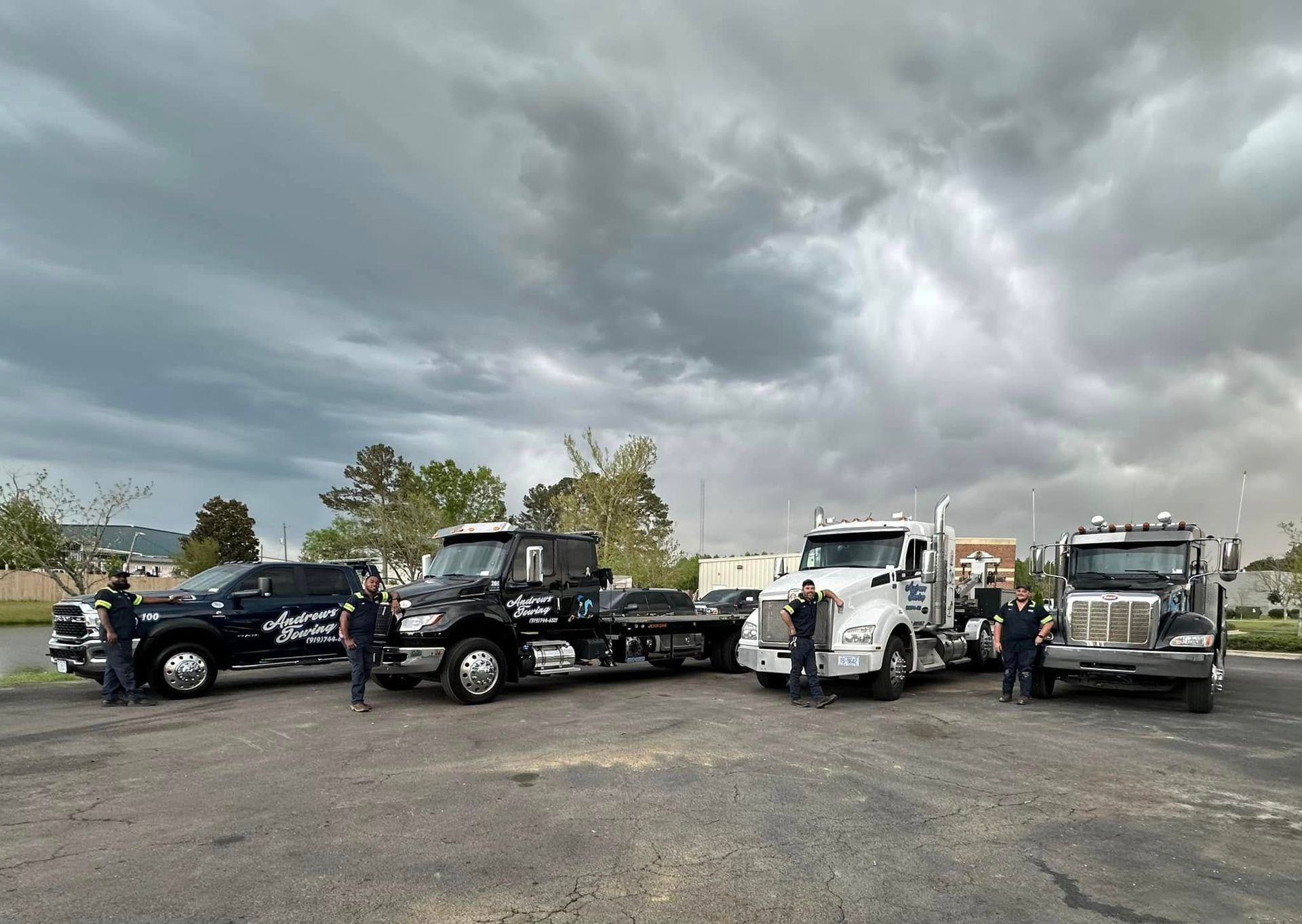 A group of tow trucks are parked in a parking lot.