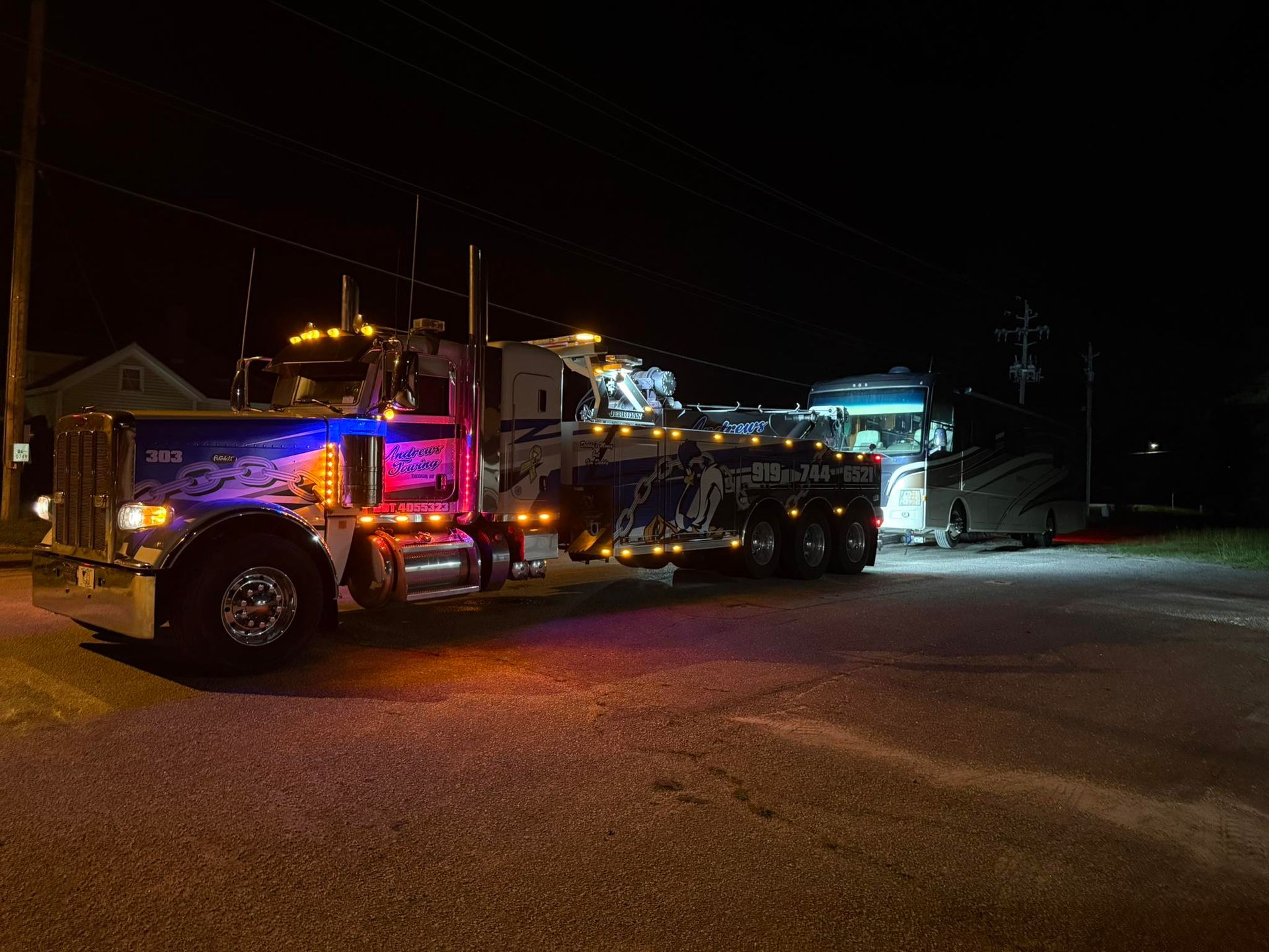 A tow truck is parked on the side of the road at night.