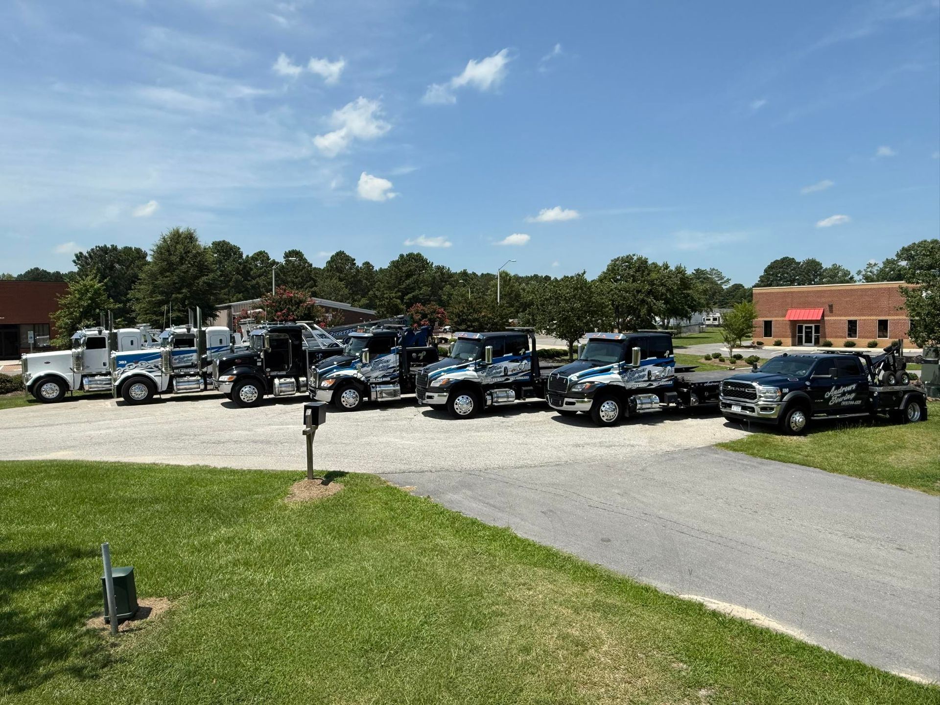 A row of tow trucks are parked in a parking lot.