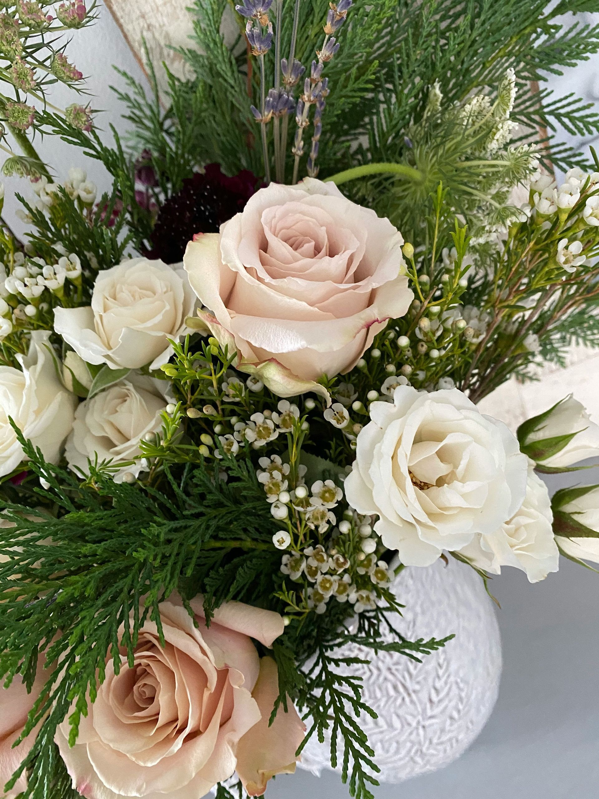 Pastel rose and white floral arrangement with greenery in a white vase