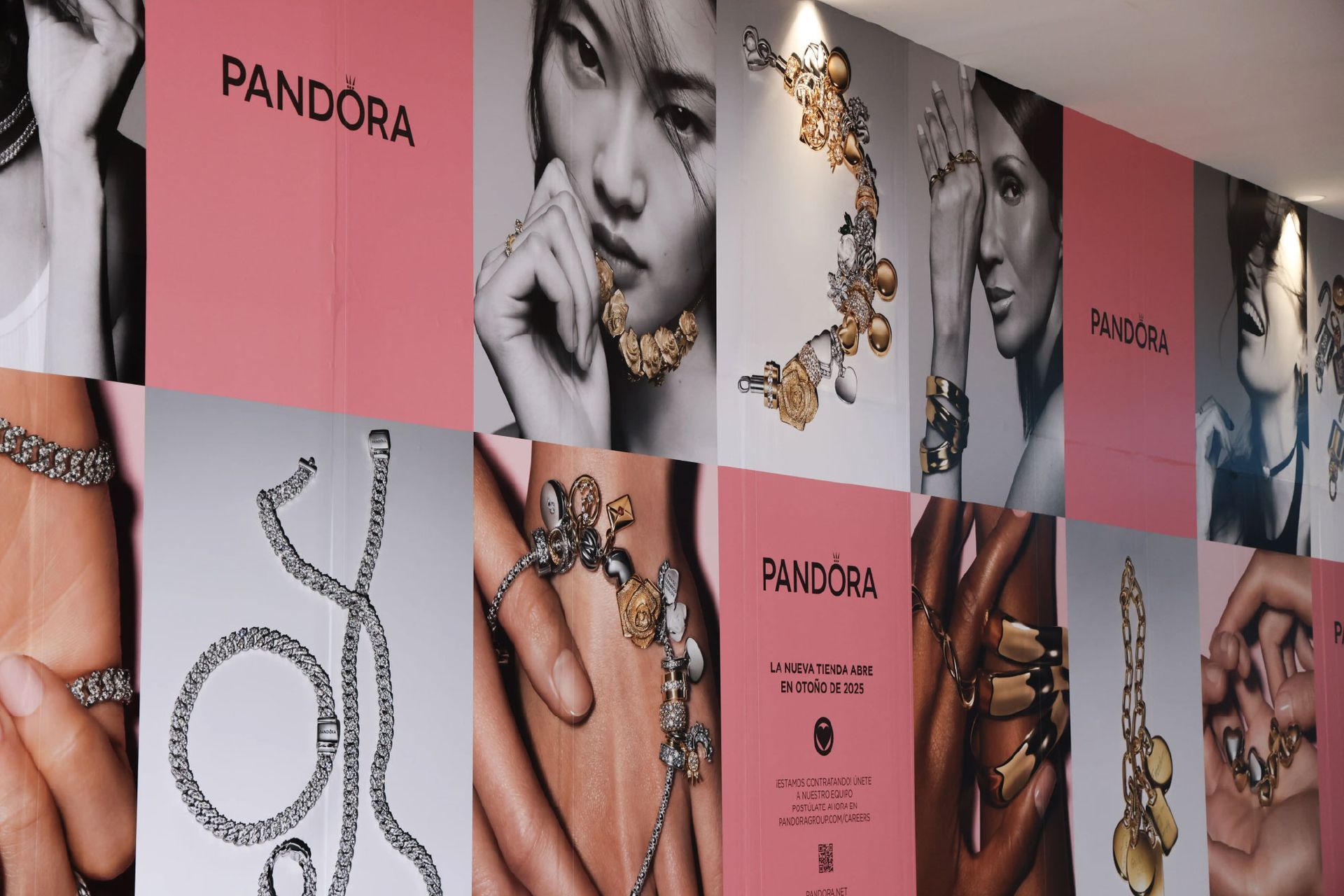 Pandora jewelry advertisement wall: photos of models wearing jewelry, on pink and white panels.
