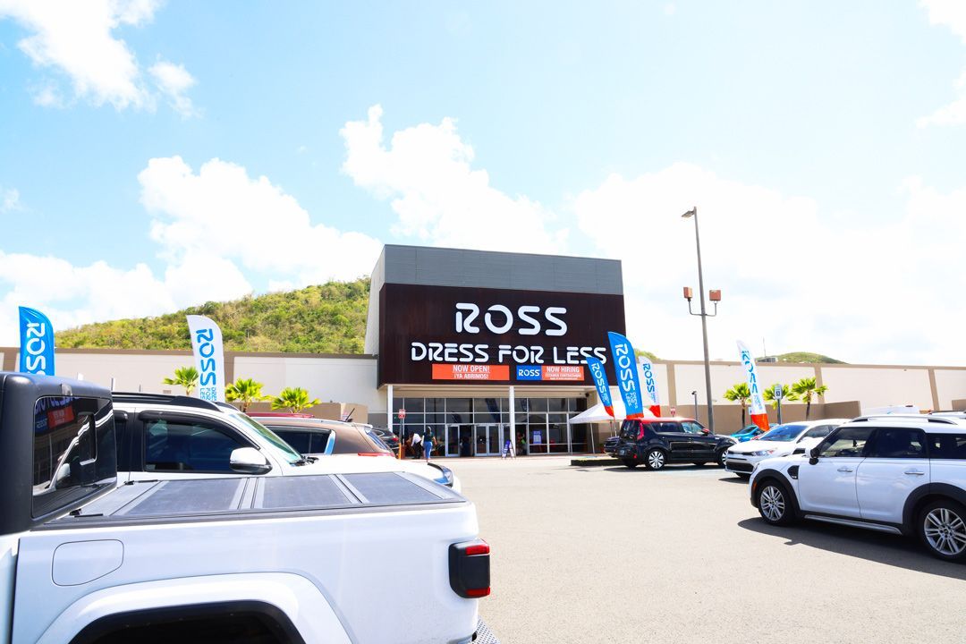 Ross Dress for Less store front lit at night with white sign and entrance, parked cars in lot.