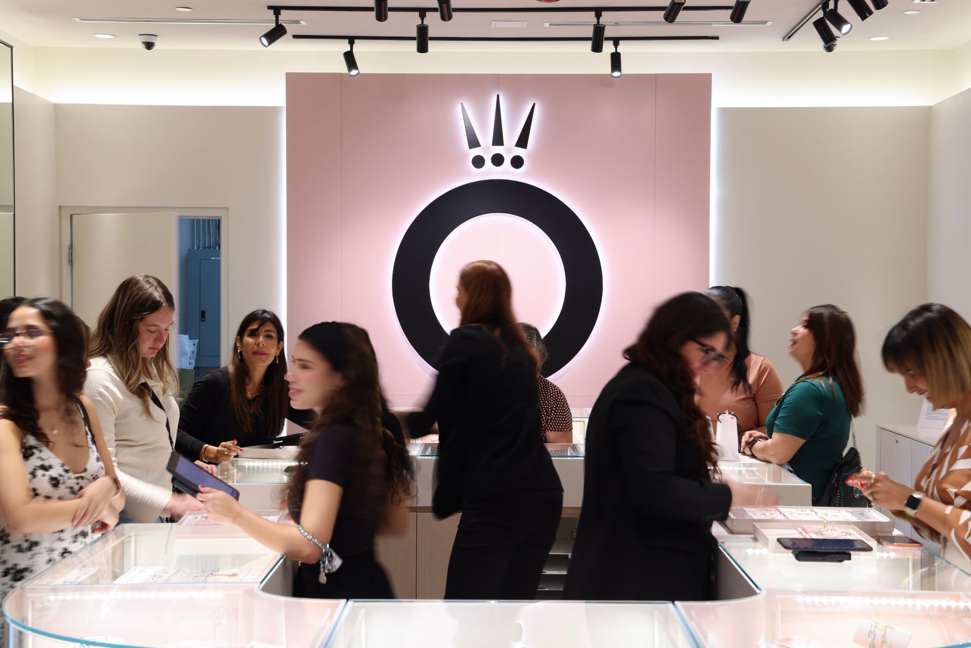 Inside a Pandora store, customers at a counter beneath the brand's logo.