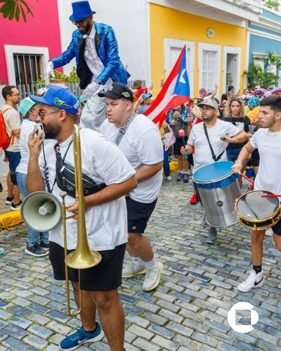 Street parade in Old San Juan: musicians, stilt walker, Puerto Rican flag, crowd, colorful buildings.