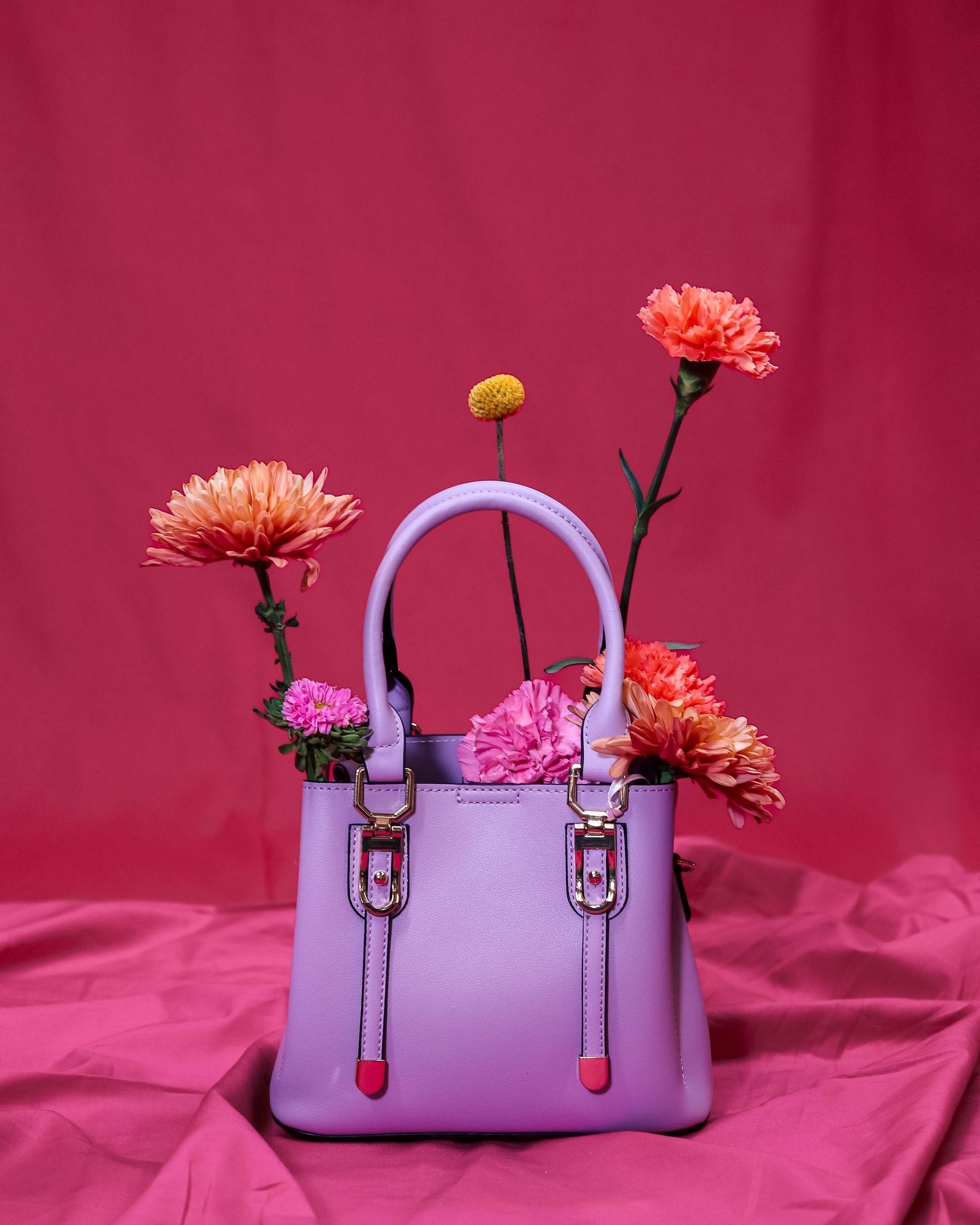 Lavender handbag with pink flowers against a bright pink backdrop