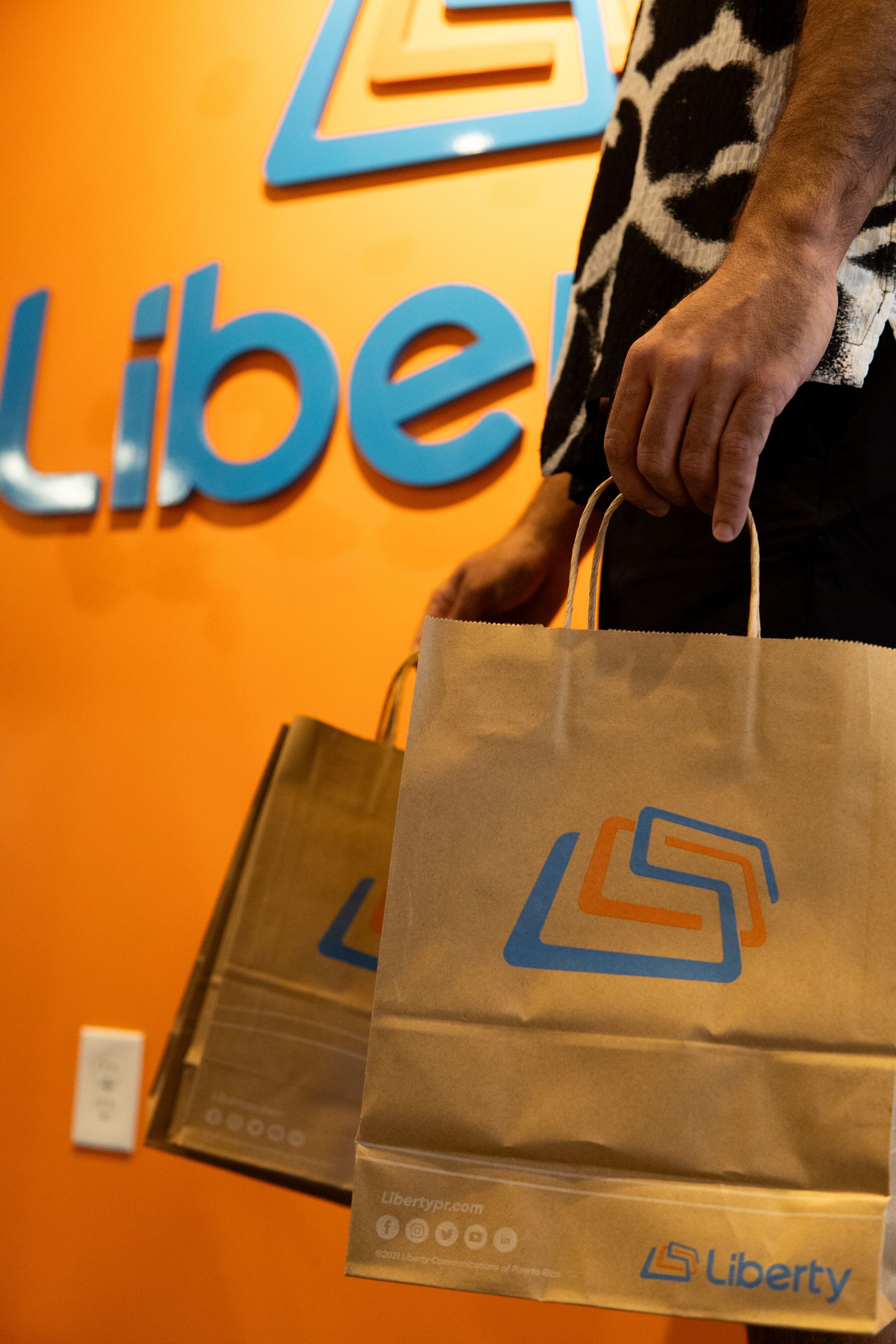 Two people smiling while holding ice cream cones in front of a pink and white abstract mural.
