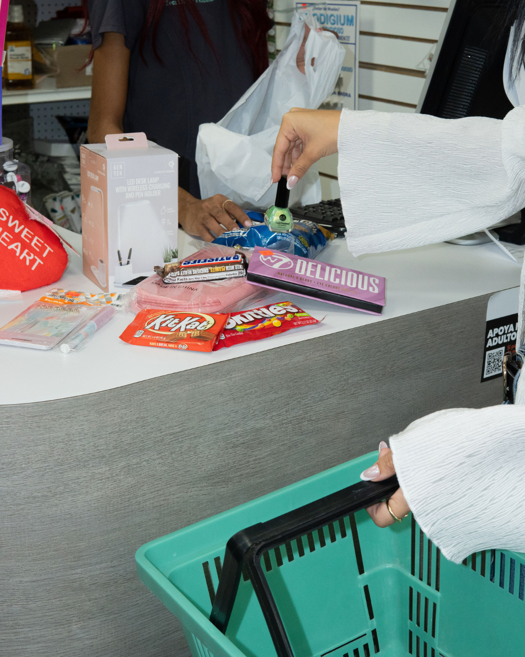 Person paying for items at a store counter. Candy, basket, and products are visible.
