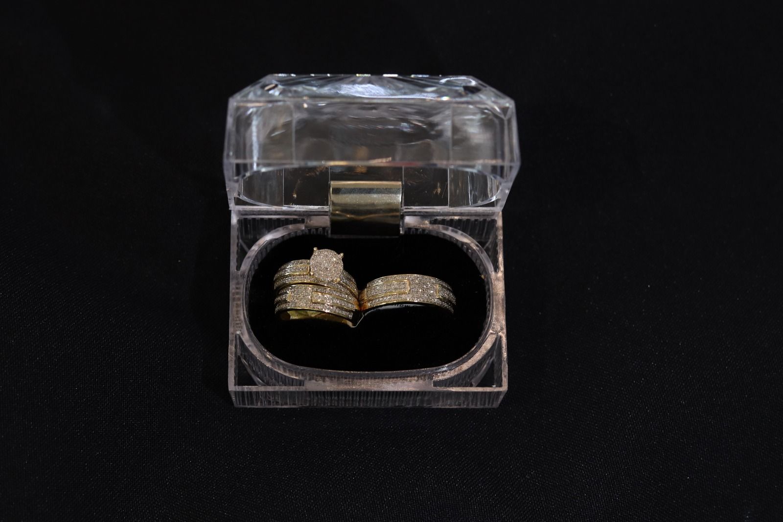 A couple of rings in a clear plastic box on a black background.