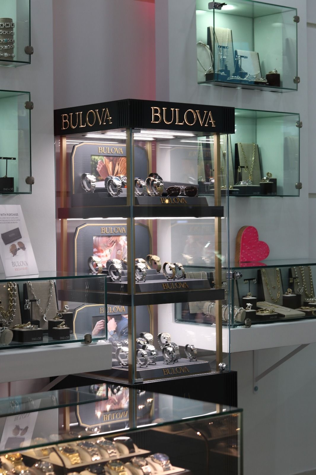 Jewelry store display case with Bulova watches. Black and gold lettering atop a glass display with multiple shelves.