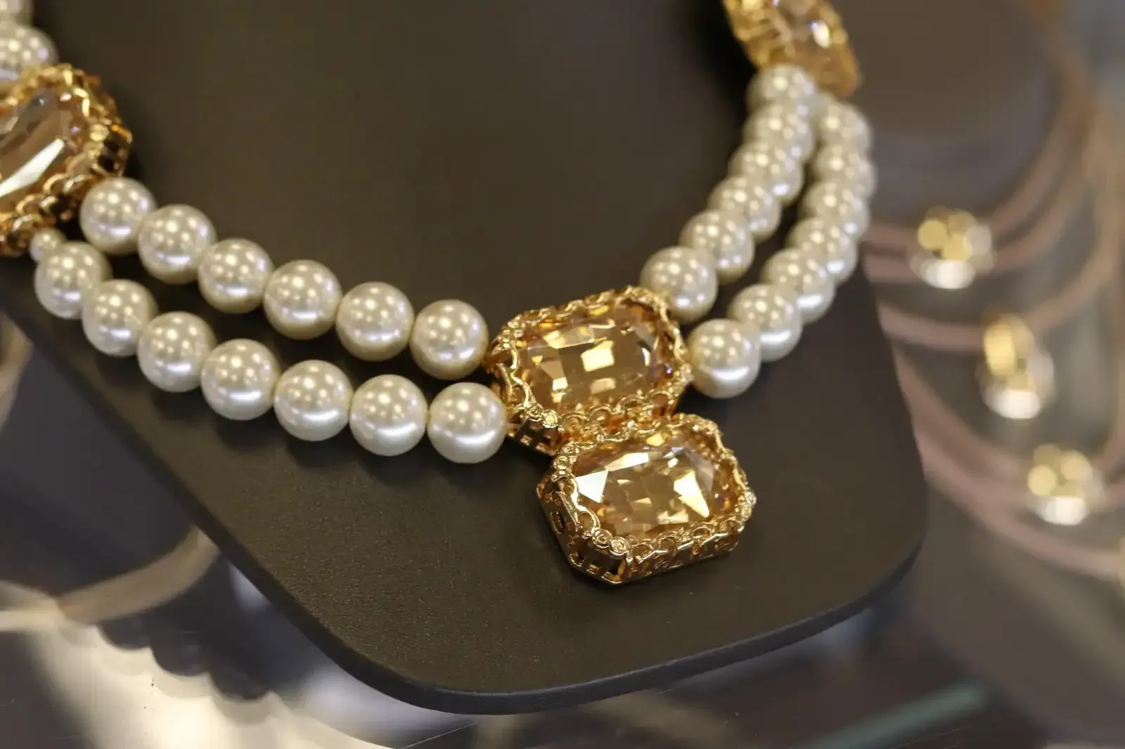 A necklace with pearls and gold pendants on a mannequin