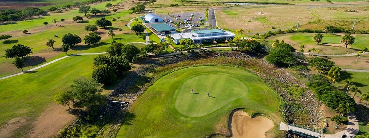 An aerial view of a golf course with a house in the background.