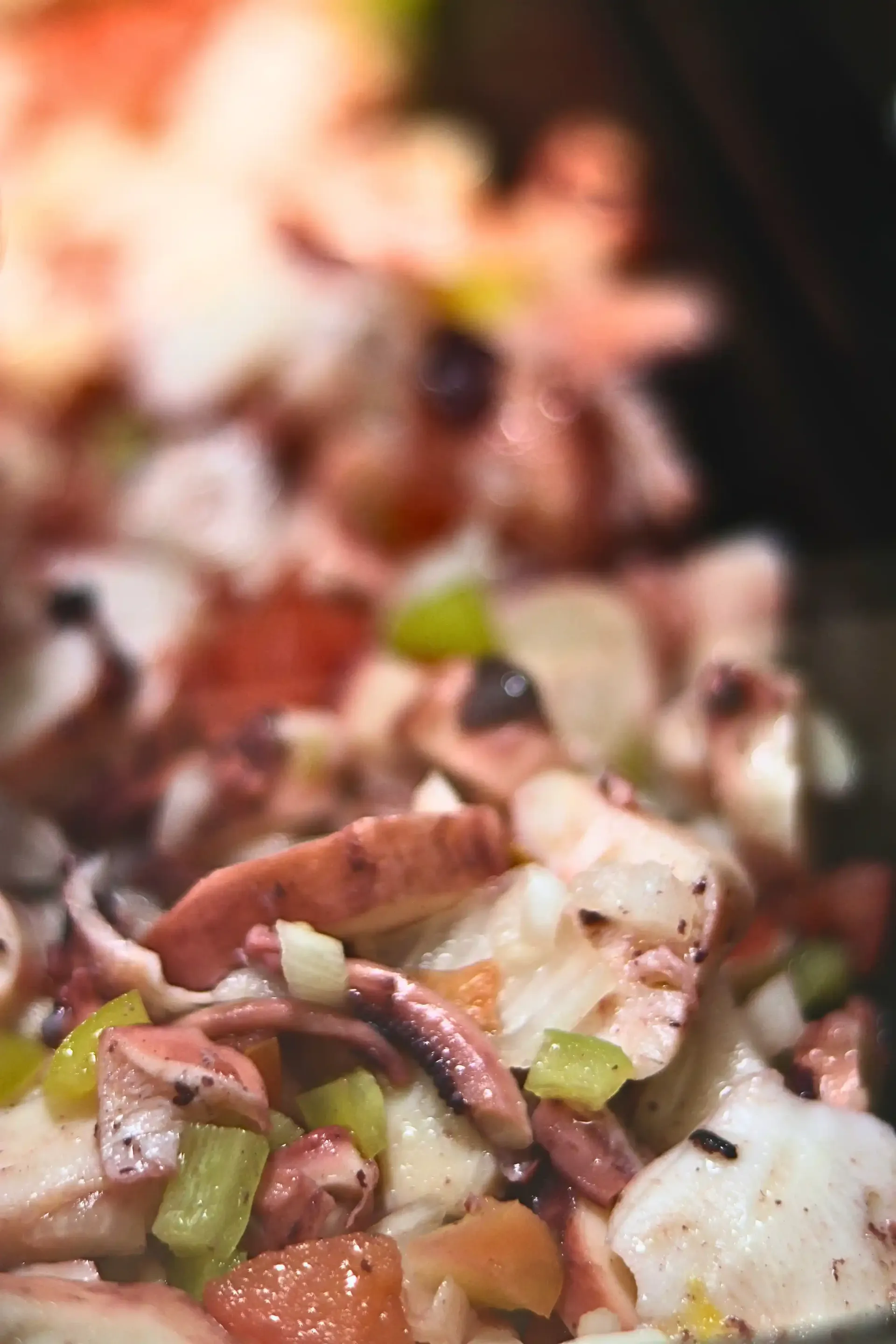 Close-up of octopus salad with chunks of seafood and vegetables.