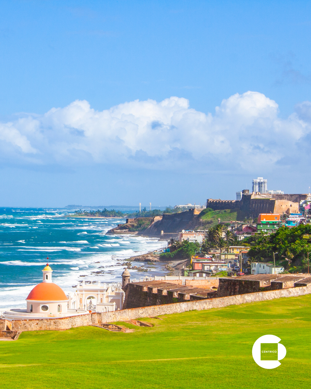 San Juan Puerto Rico with historic stone fort and church on a sunny day with blue sky and ocean waves.