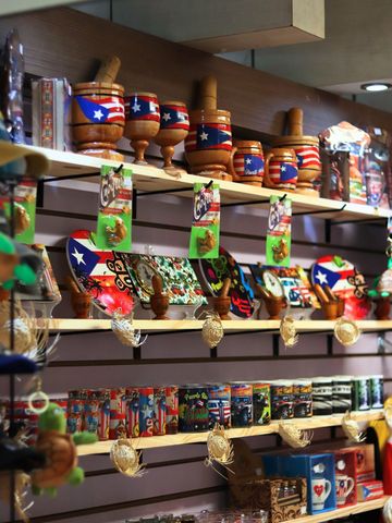 Shelves displaying Puerto Rican souvenirs: mugs, plates, and wooden mortar and pestle sets decorated with the Puerto Rican flag.