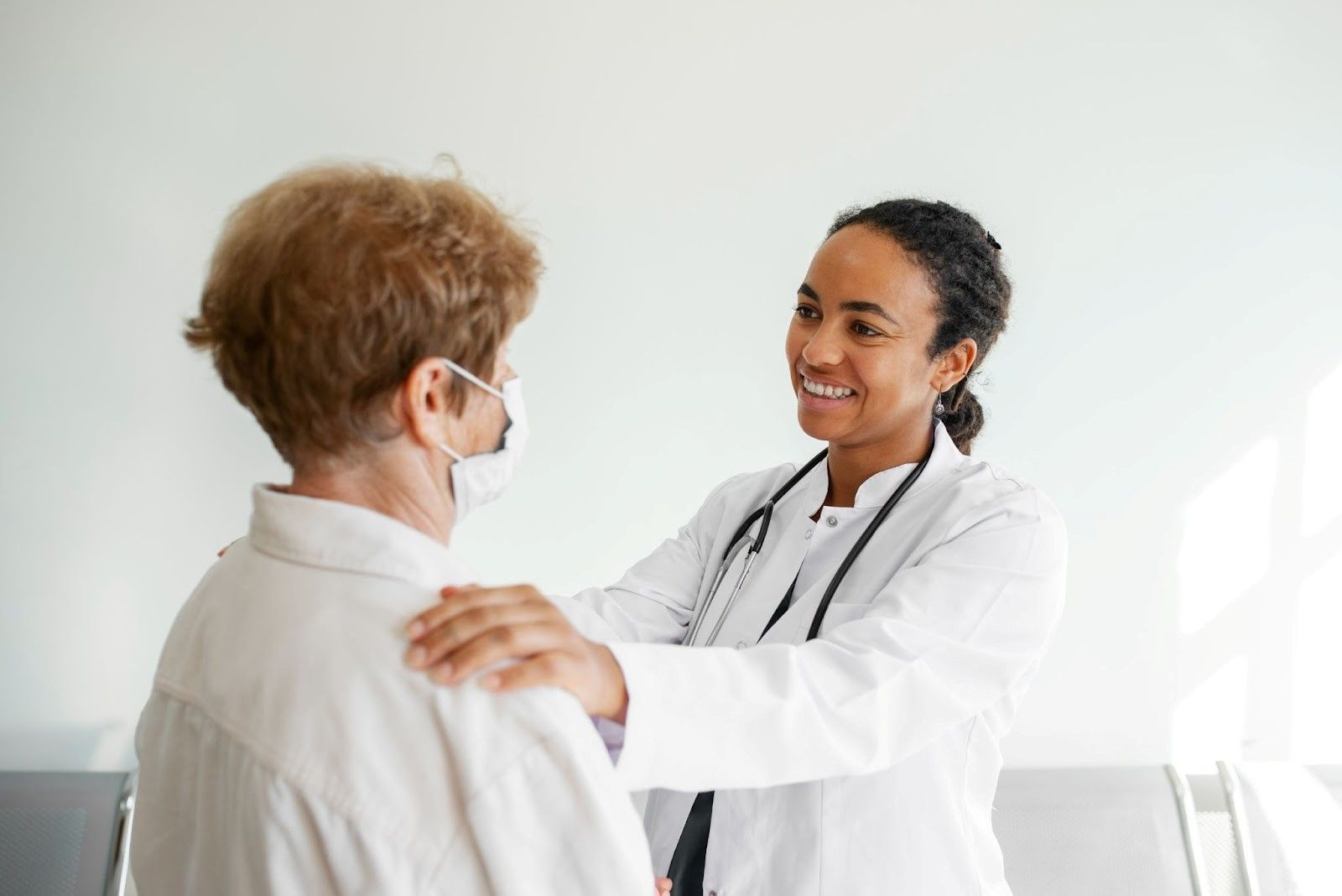 Female doctor in white coat comforting an elderly patient, showing ethical recruitment practice