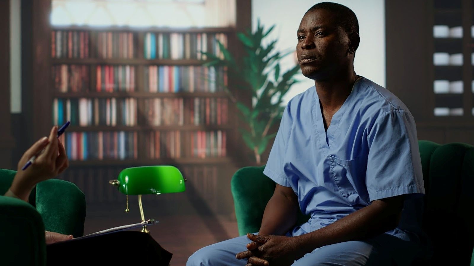 Male healthcare worker in blue scrubs sitting thoughtfully in an office, reflecting on recruitment ethics