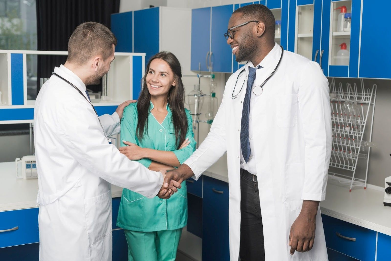 Two male doctors shaking hands with a smiling female nurse in a clinic, symbolising trust in ethical recruitment