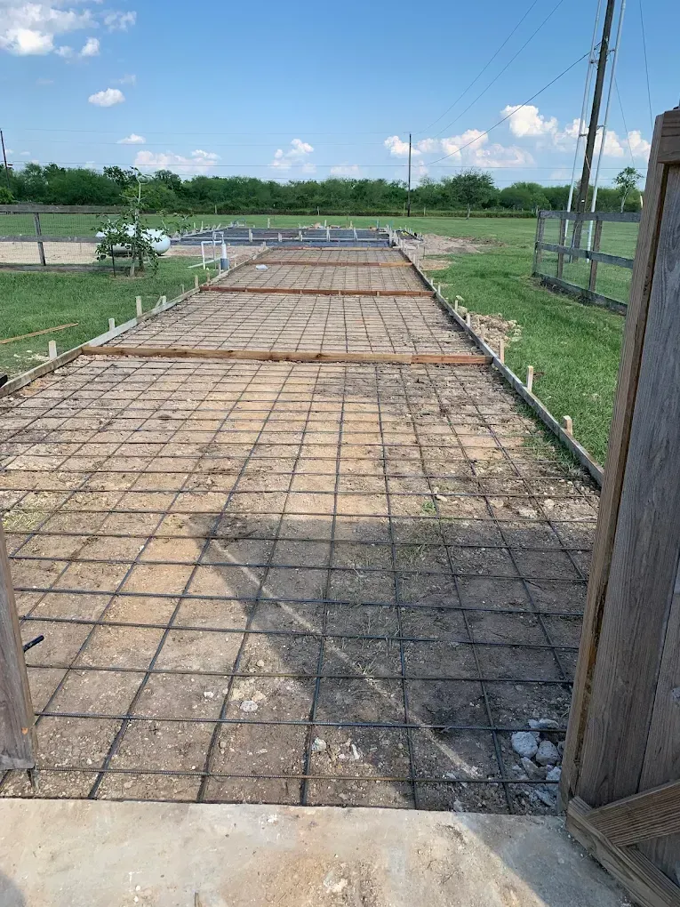 A concrete driveway is being built in a field.