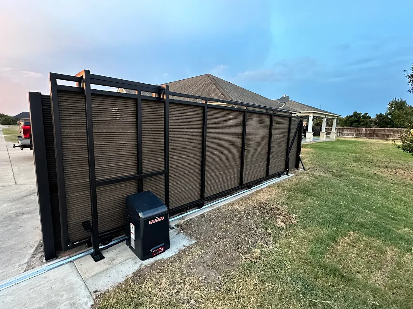 A sliding gate with a motor attached to it is in front of a house.