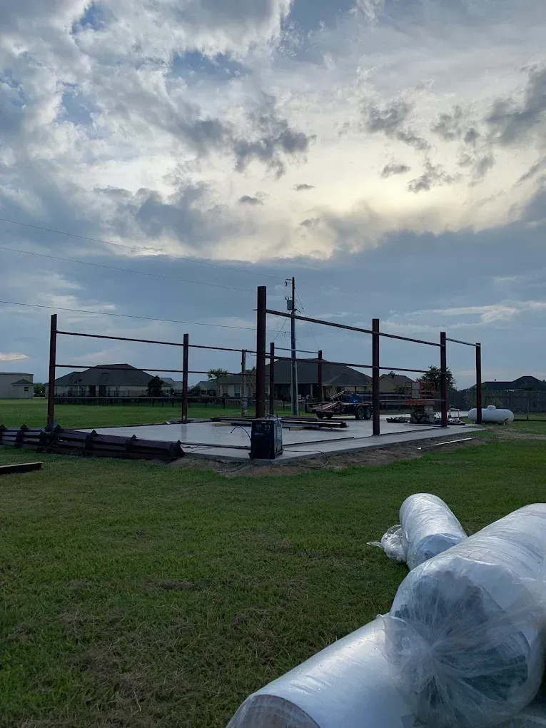 A basketball court is being built in a grassy field.