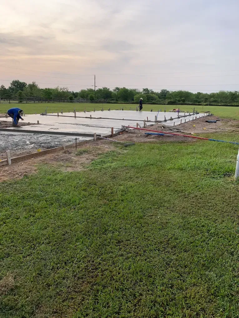 A man is working on a concrete slab in a field.