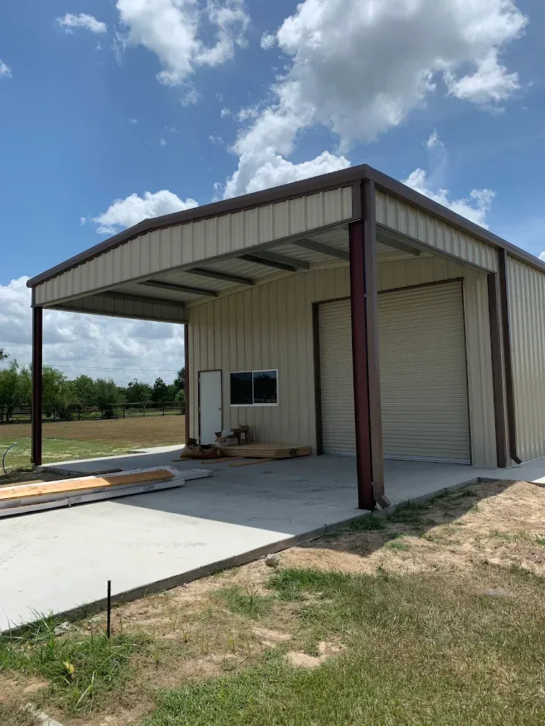 A metal building with a garage door is being built in a field.
