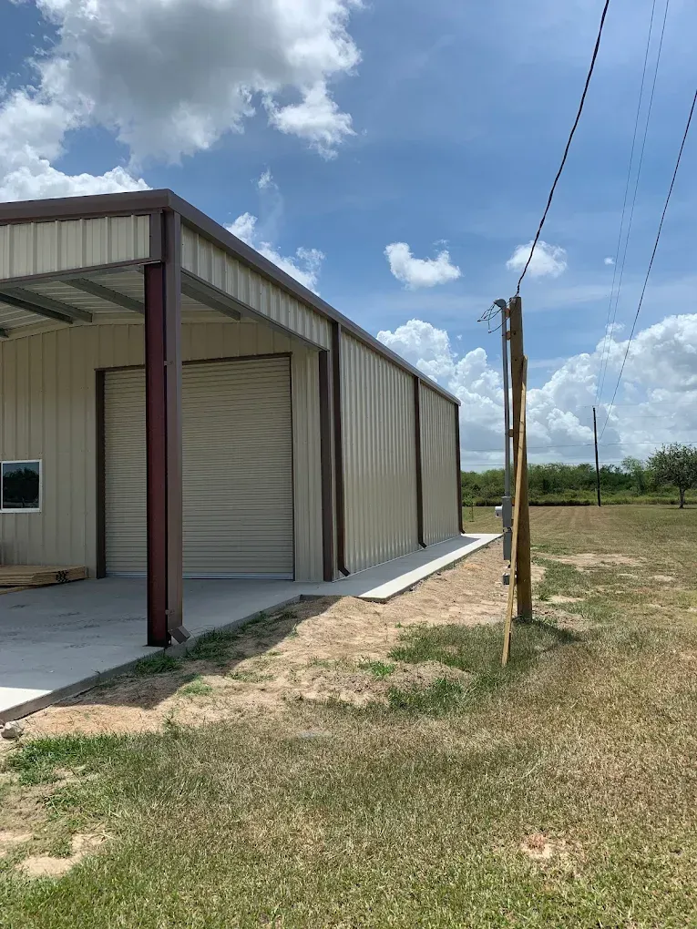 A metal building with a garage door is being built in a field.