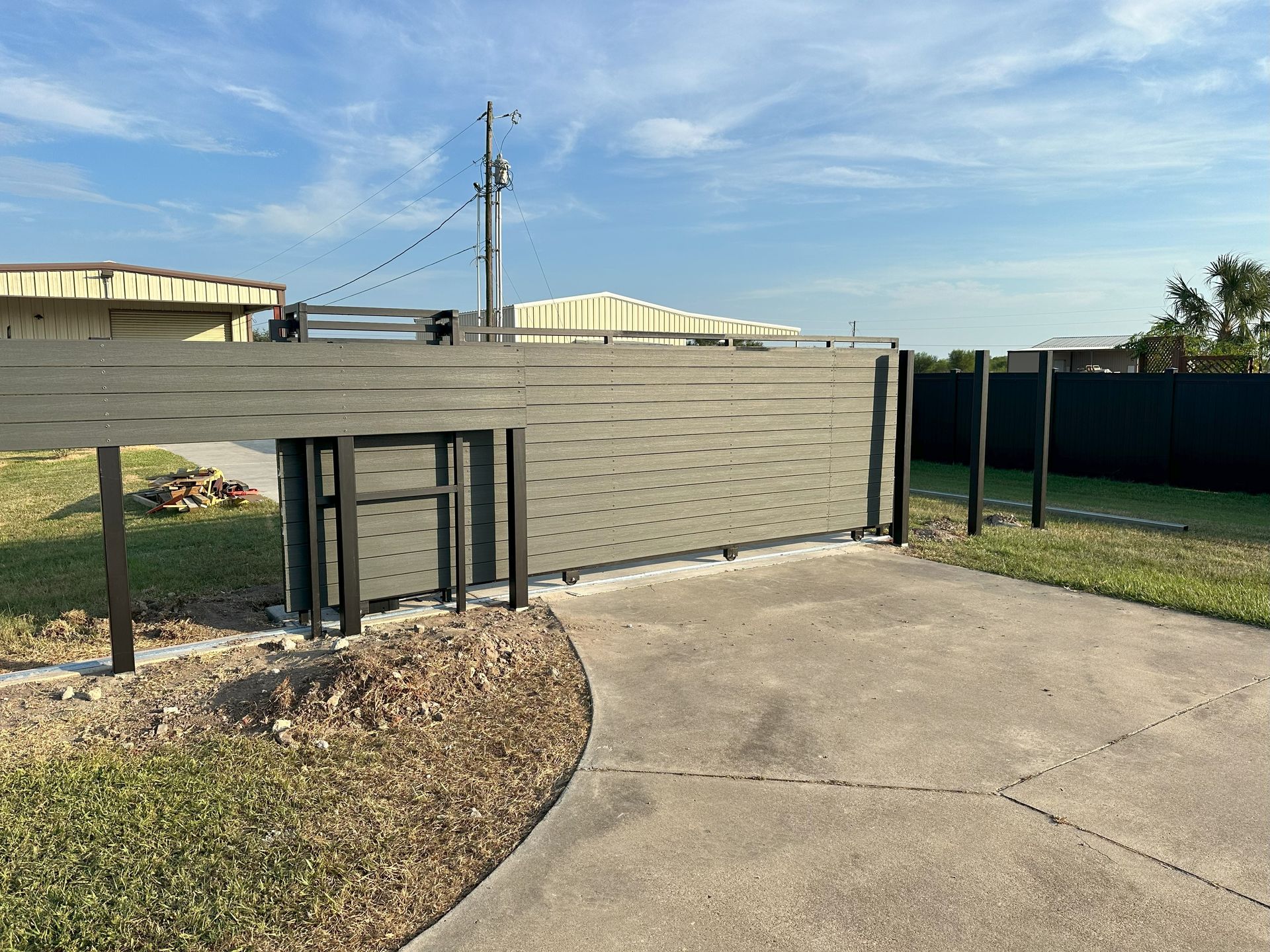 A fence with a sliding gate in the middle of a driveway