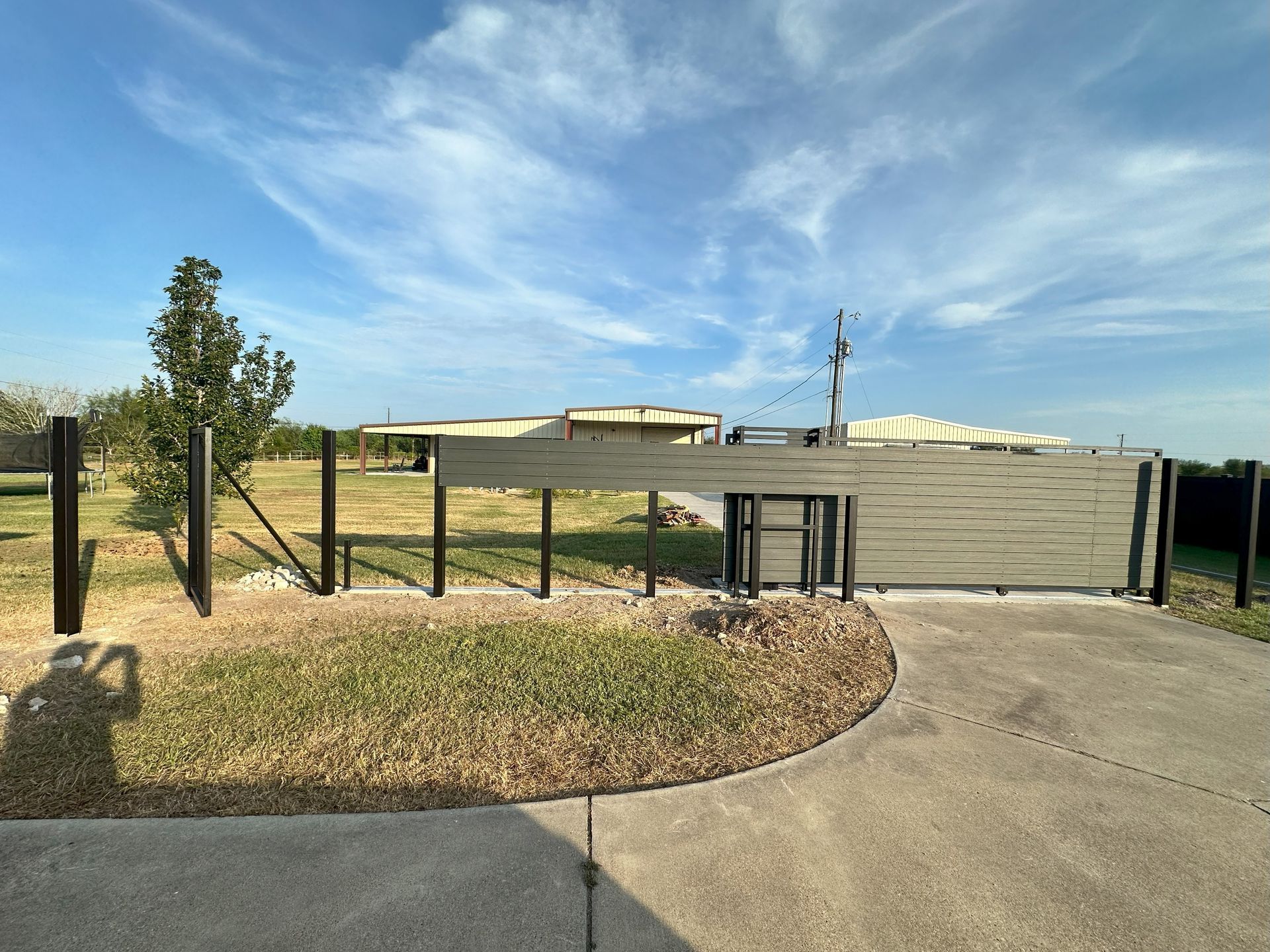 A driveway with a fence and a gate in front of a house.