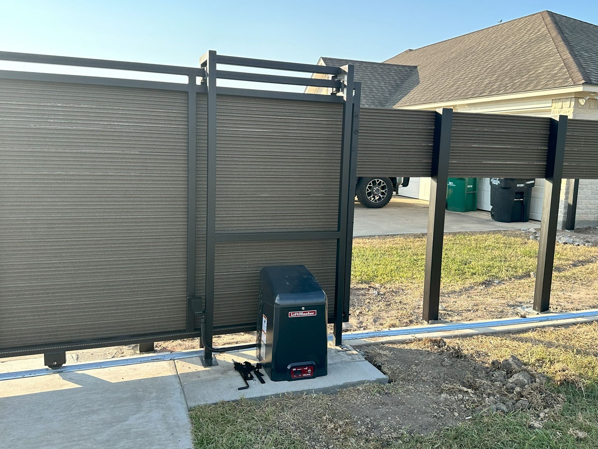 A sliding gate with a motor attached to it in front of a house.