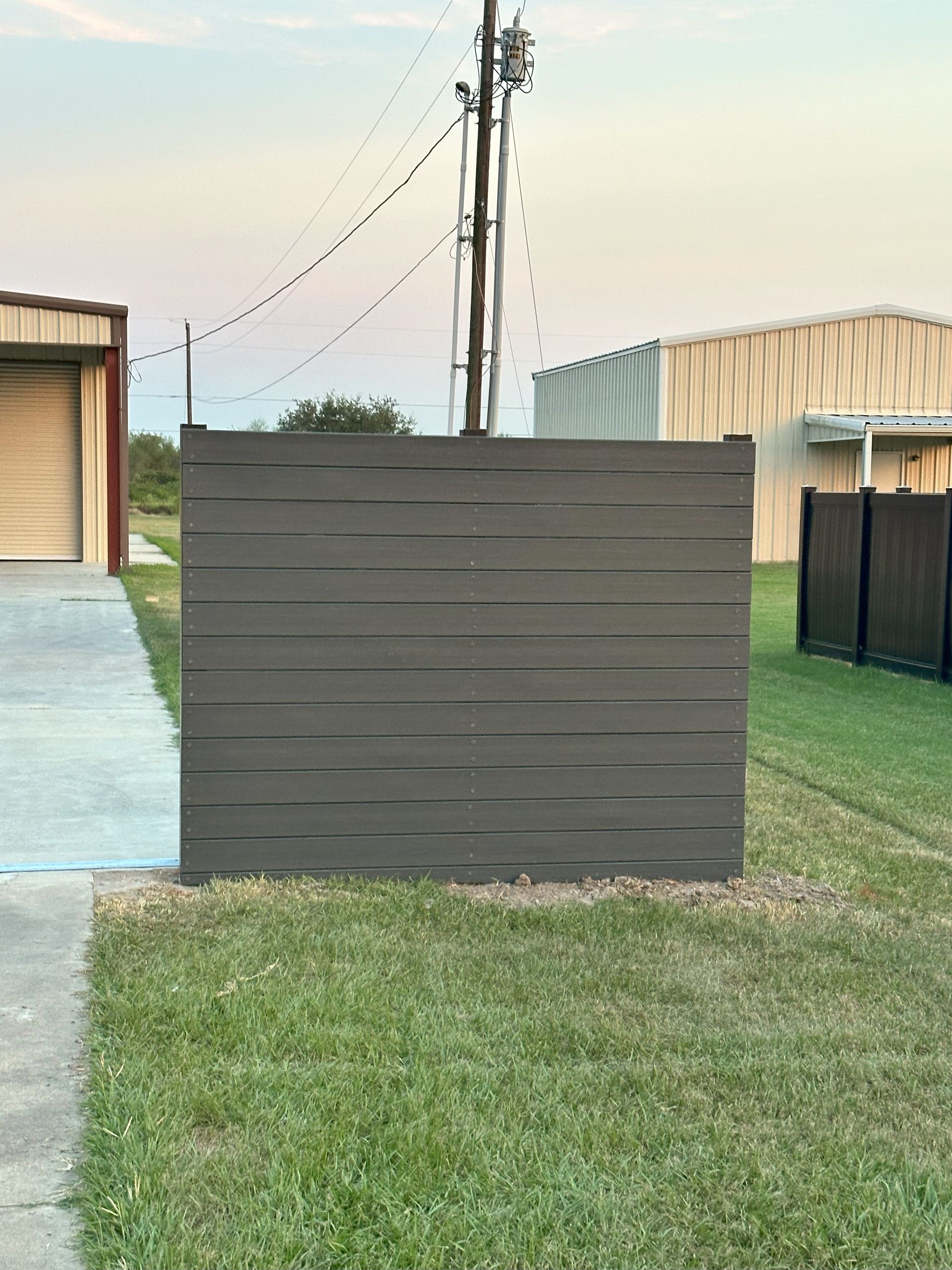A large wooden fence is in the middle of a lush green field.