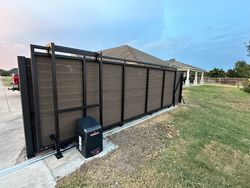 A sliding gate with a motor attached to it is sitting in front of a house.