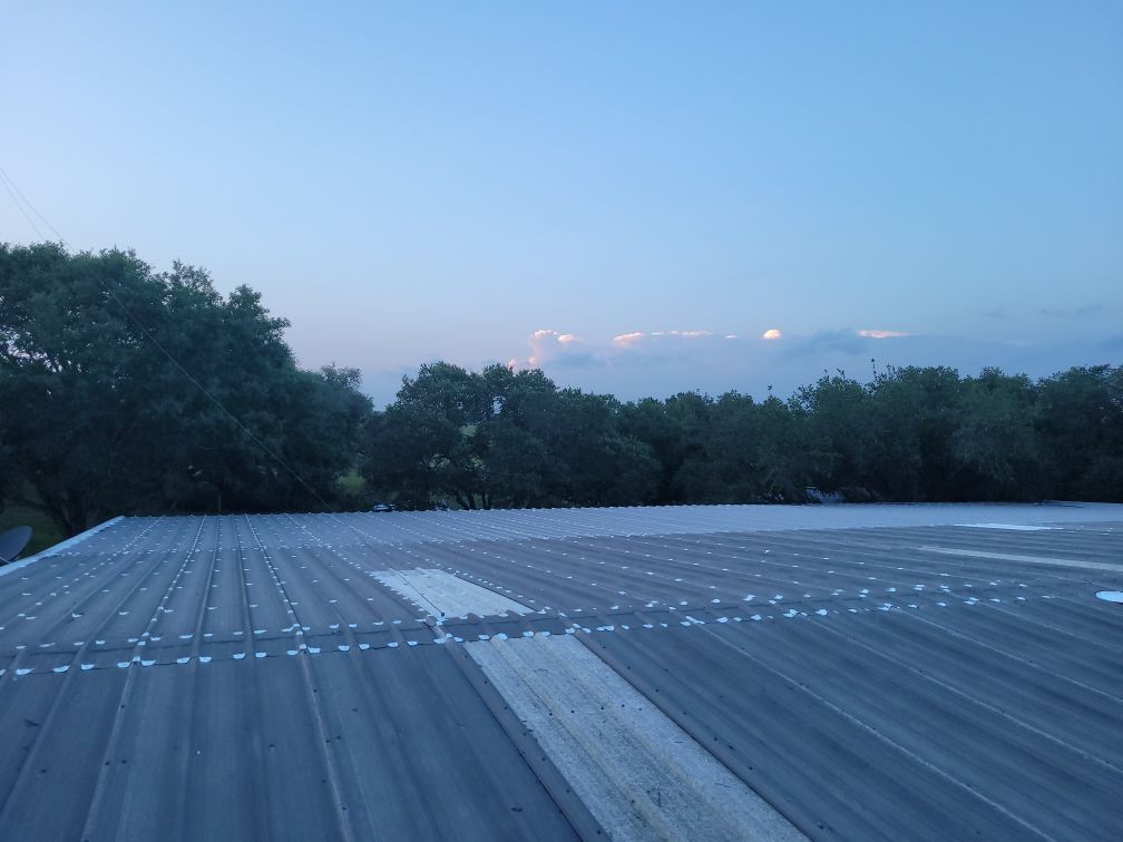 A roof with trees in the background and a blue sky