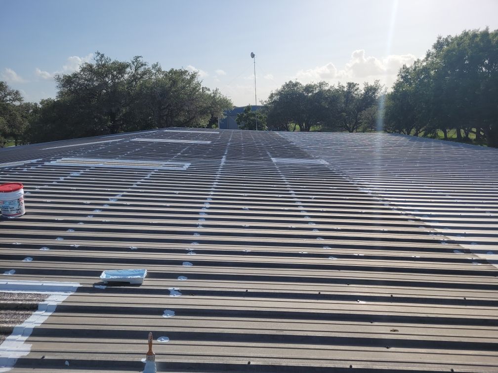 The roof of a building is being painted with white paint.