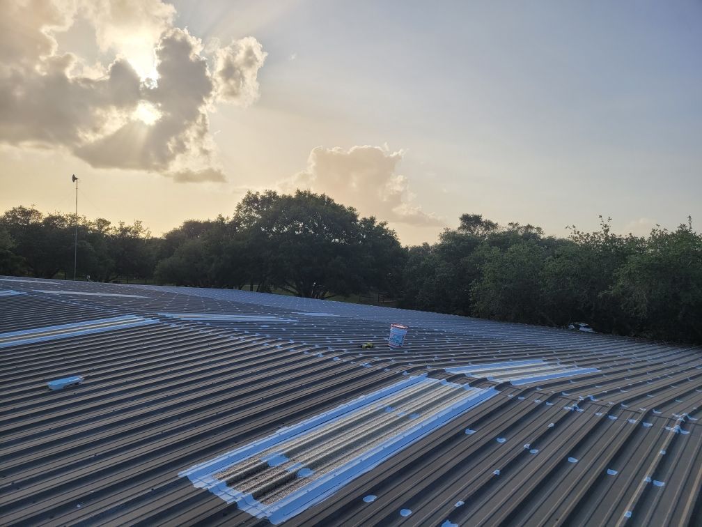 A roof with a sunset in the background and trees in the foreground.