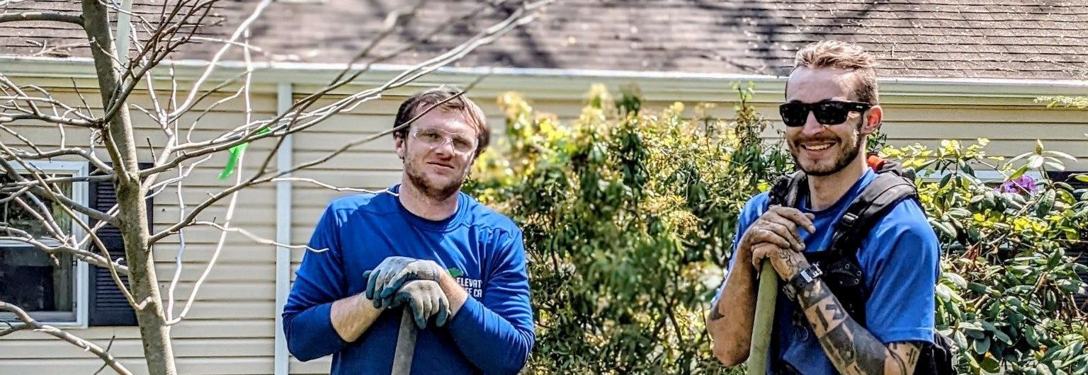 Two men are standing next to each other in front of a house.