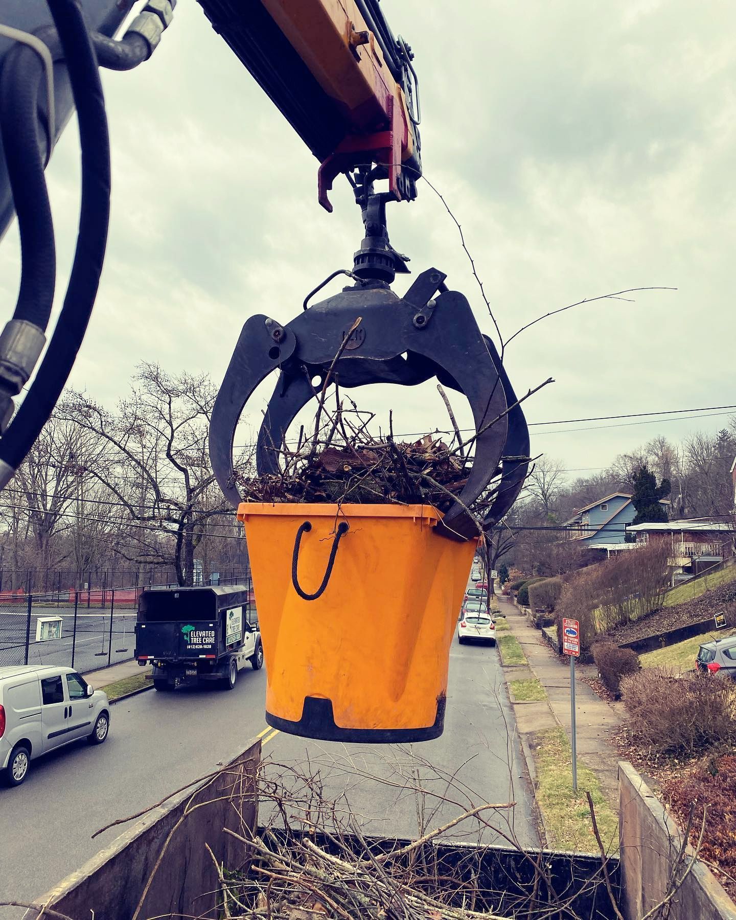 A yellow bucket is being lifted by a crane