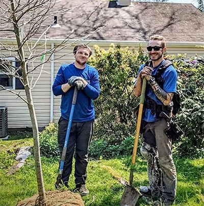 Two men are standing next to each other in front of a house.