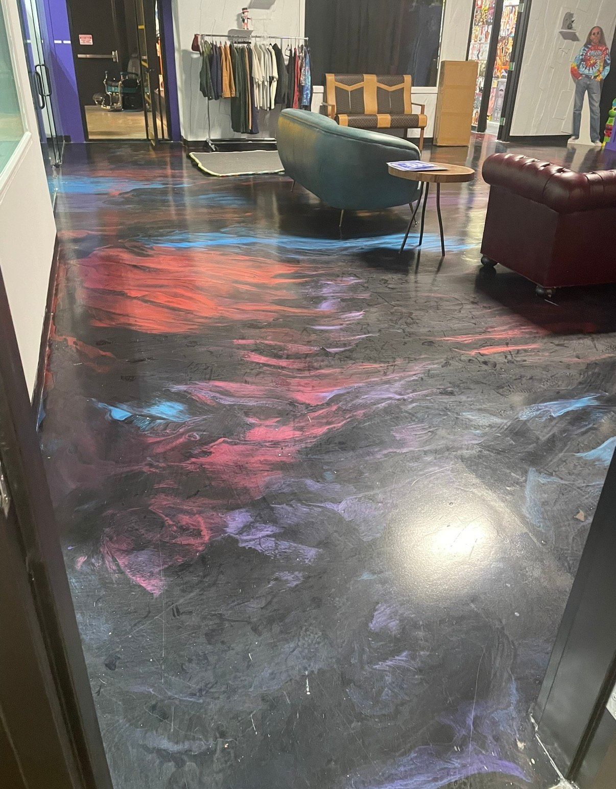 Colorful epoxy flooring in a room with furniture; purple, blue, and red swirls.