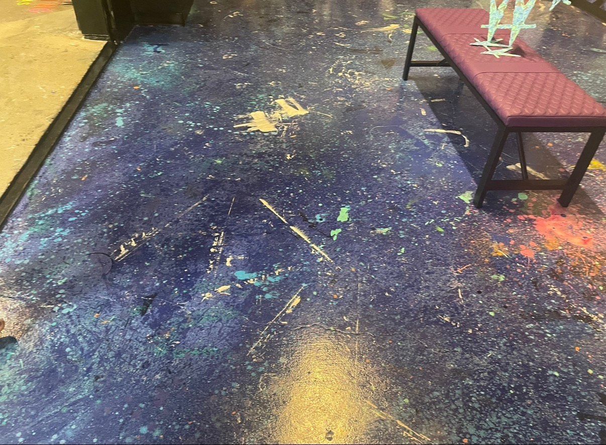 Blue speckled floor with paint splatters, next to a burgundy bench.