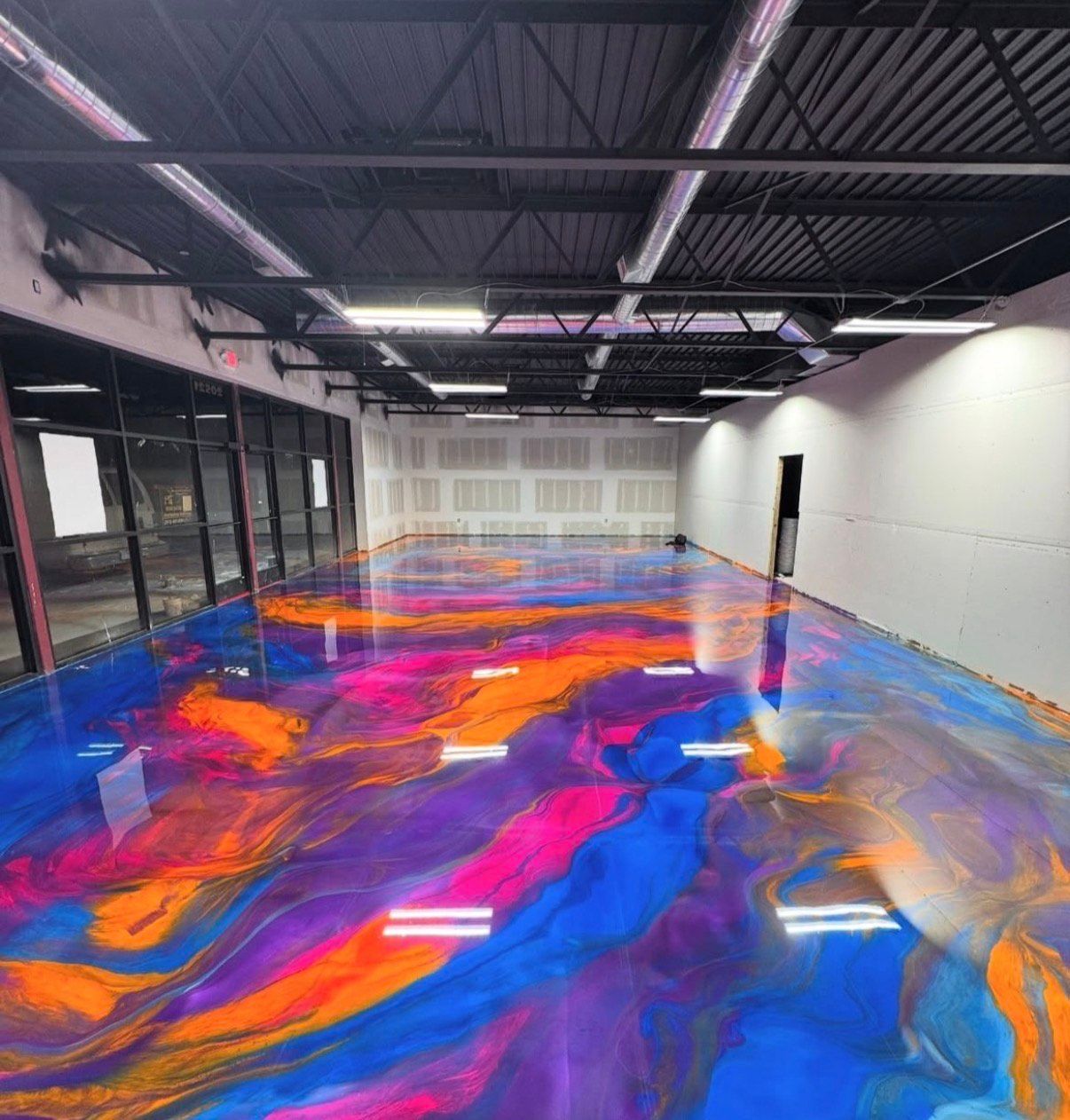 Vibrant epoxy flooring in a large room. The floor has swirling patterns of blue, orange, purple, and pink.