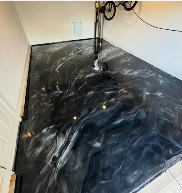 Metallic epoxy flooring in shades of black and silver, resembling a swirling galaxy, in a garage.