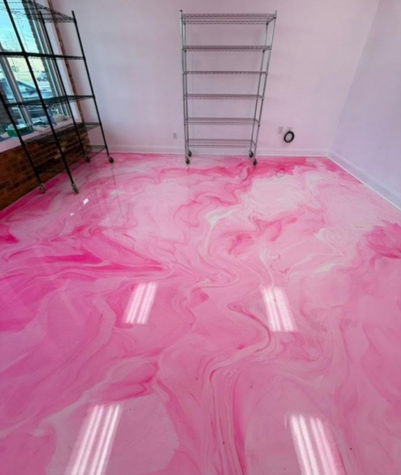 Pink and white swirled epoxy floor in a room, with metal shelving and a window.