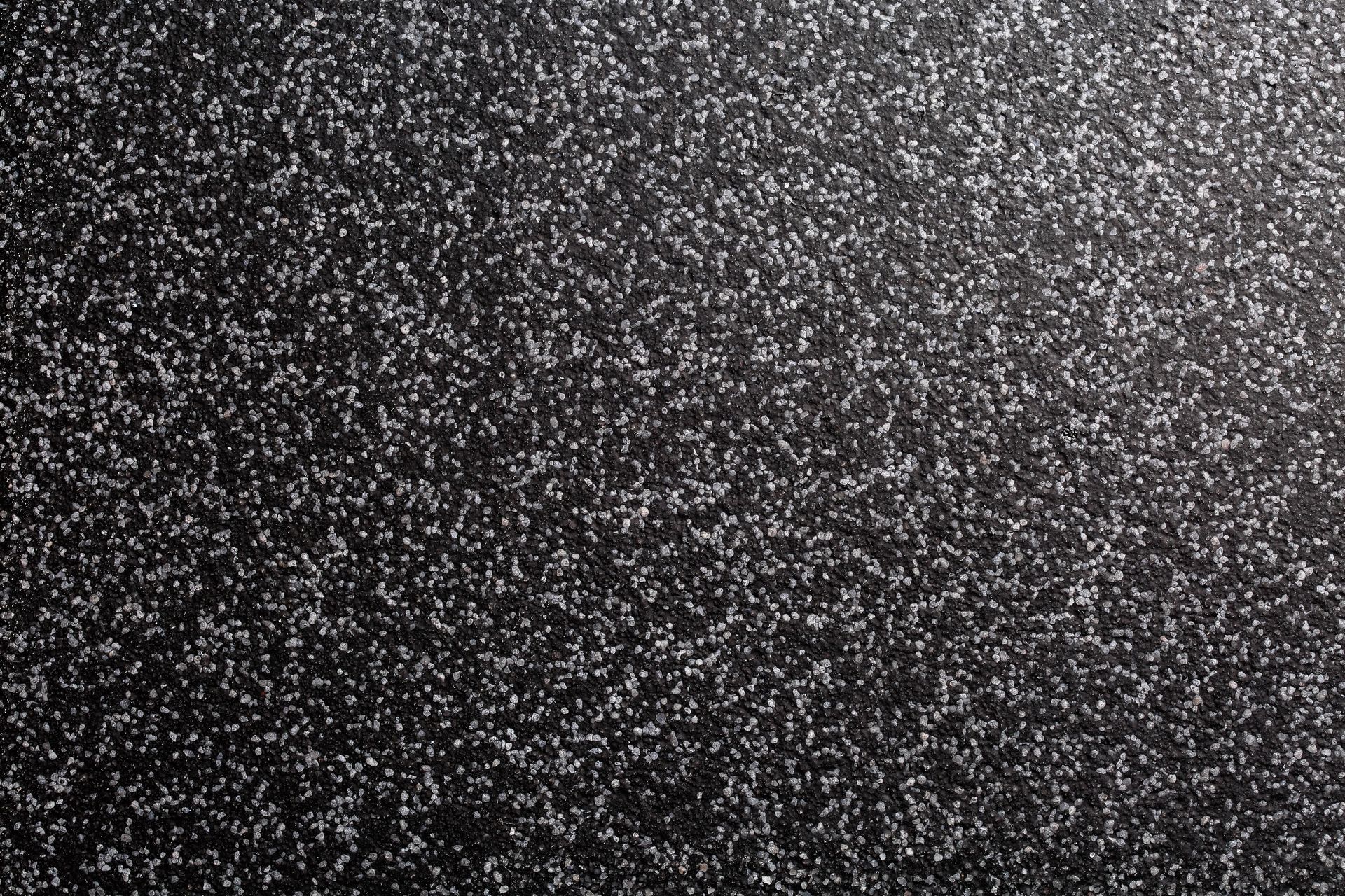 Black surface covered in tiny, white specks; resembling glitter or static.