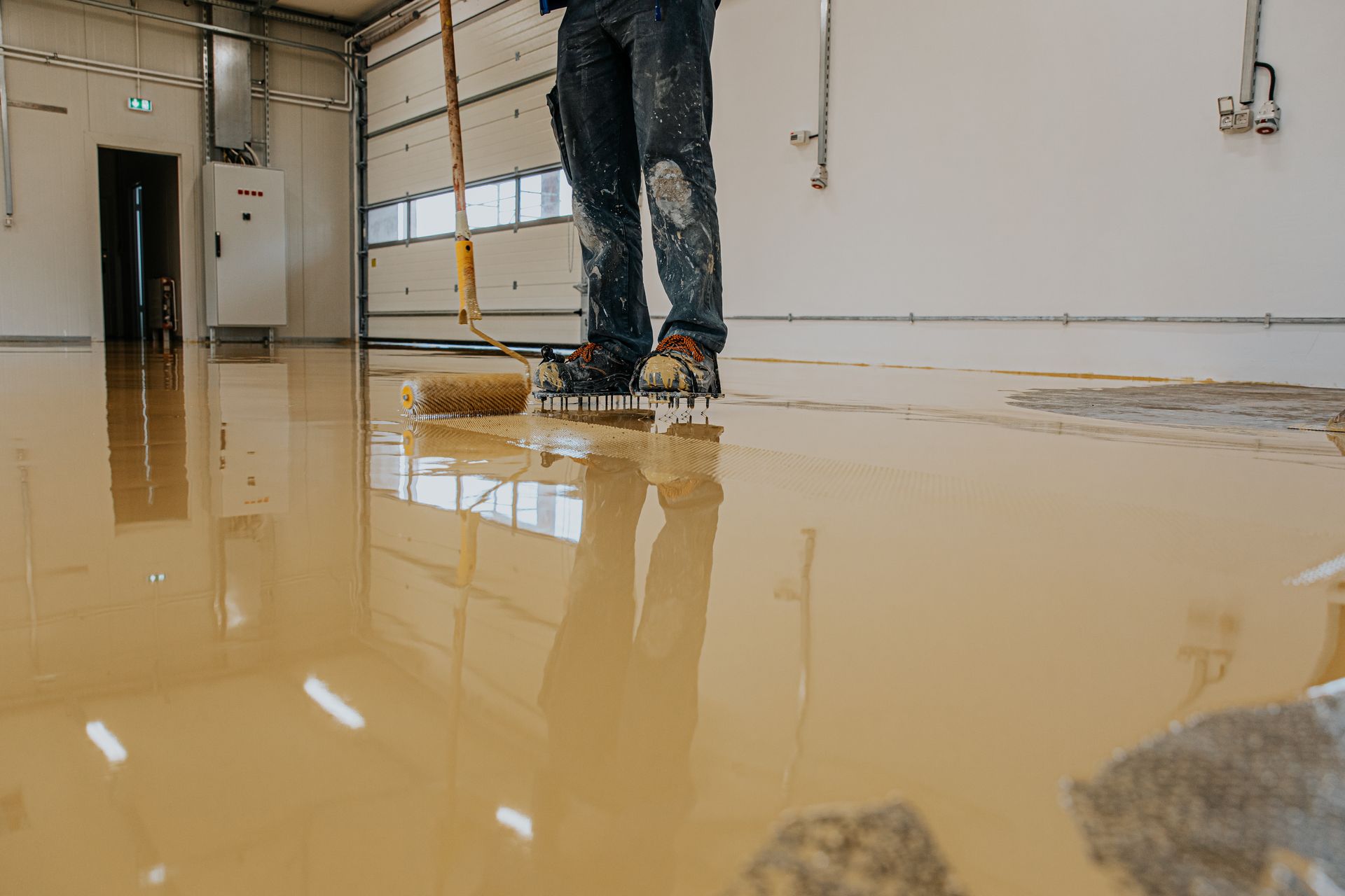 Person applying sealant to a concrete floor in a warehouse.
