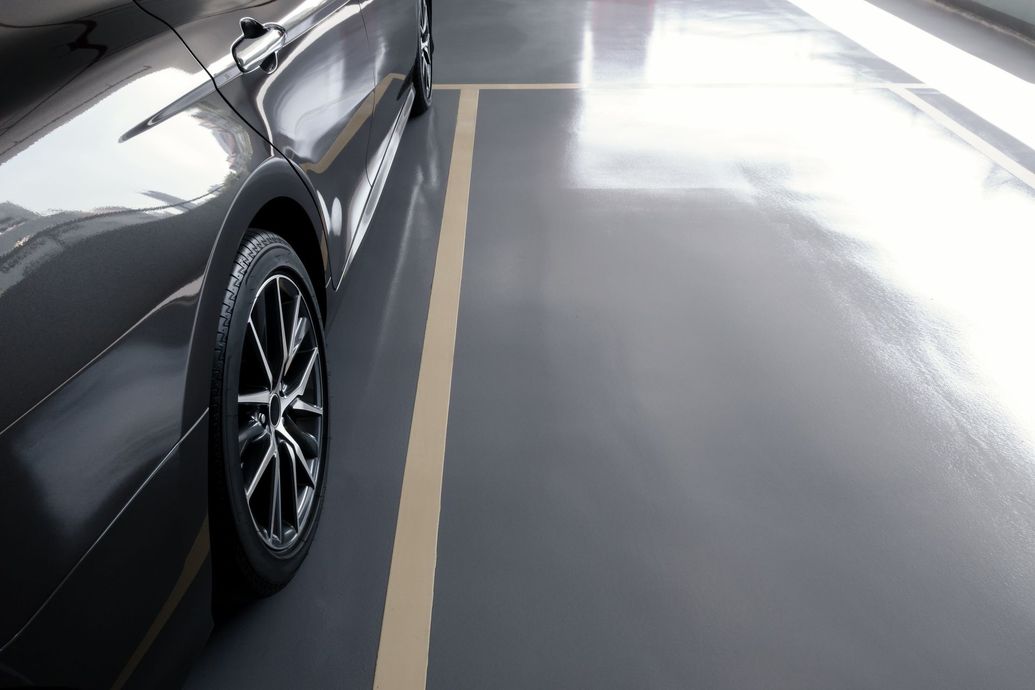 Black car parked in a gray parking space with a yellow line.