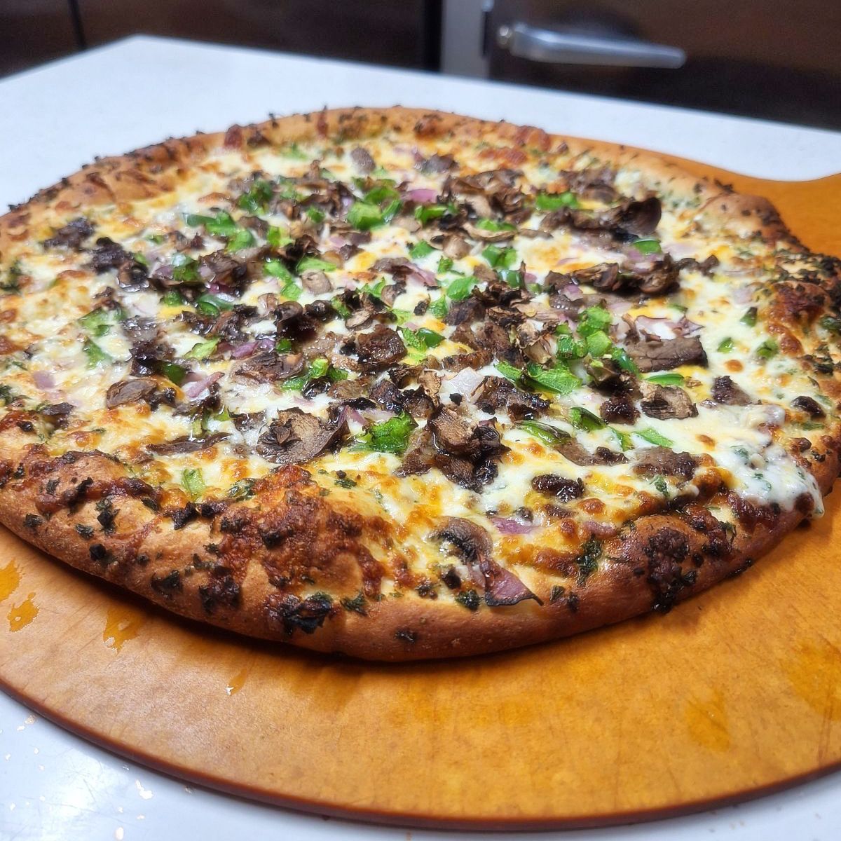 A pizza is sitting on a wooden cutting board
