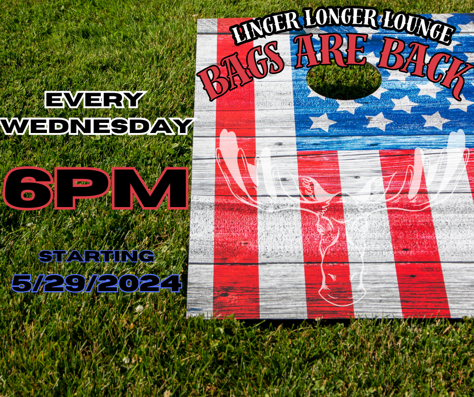 A wooden sign with an american flag on it is sitting in the grass.