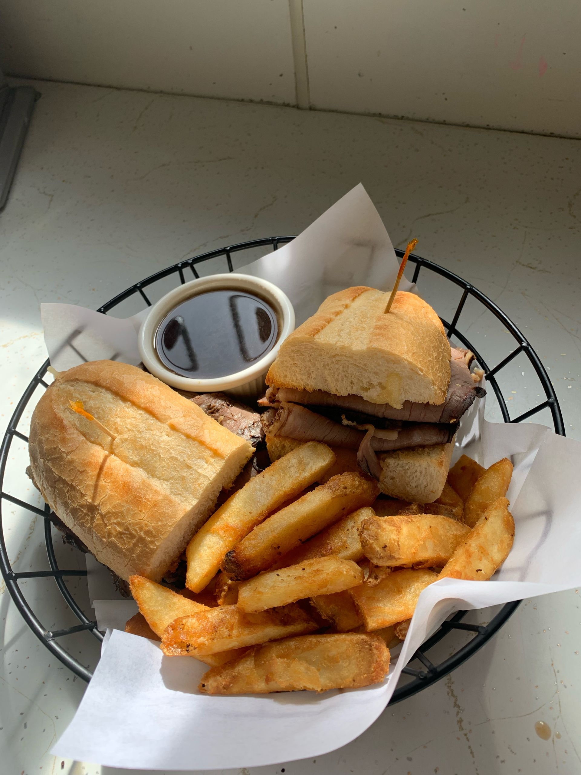 A sandwich and french fries in a basket with dipping sauce