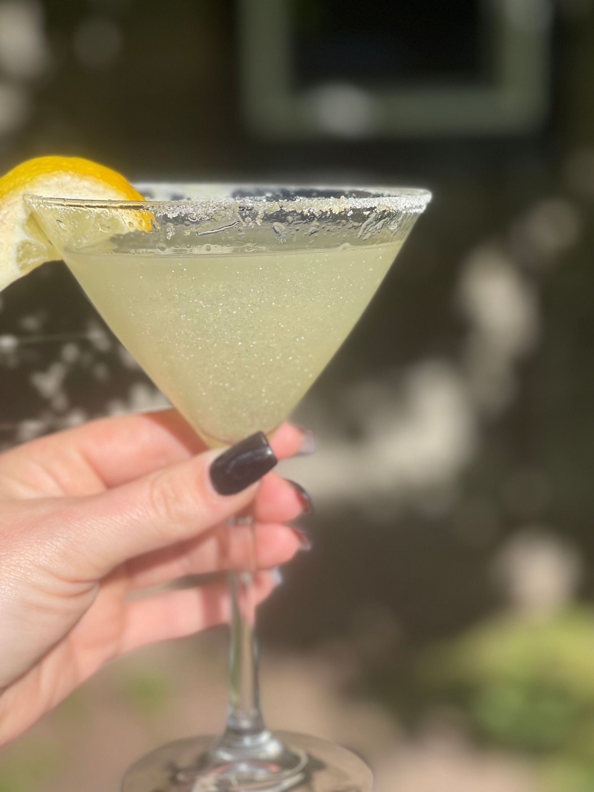 A woman is holding a martini with a lemon slice on top.